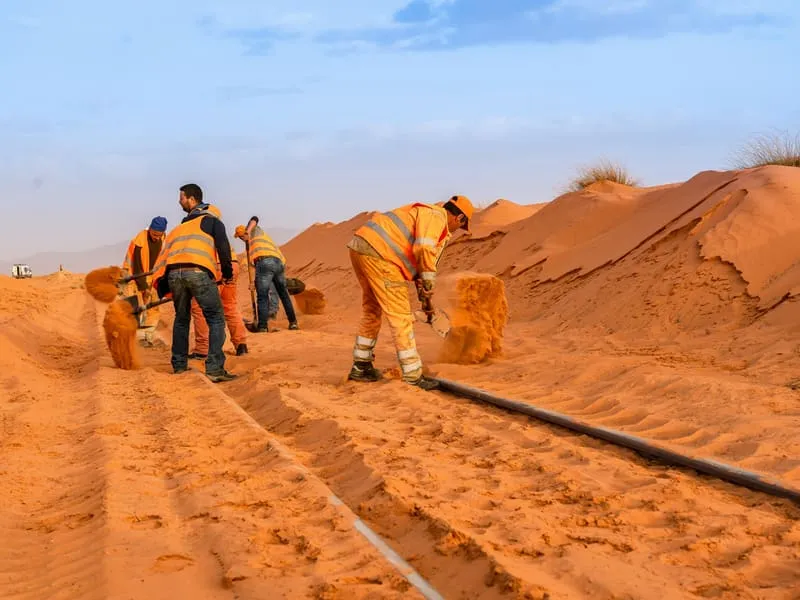 Gleisarbeiter schaufeln Treibsand von den Schienen