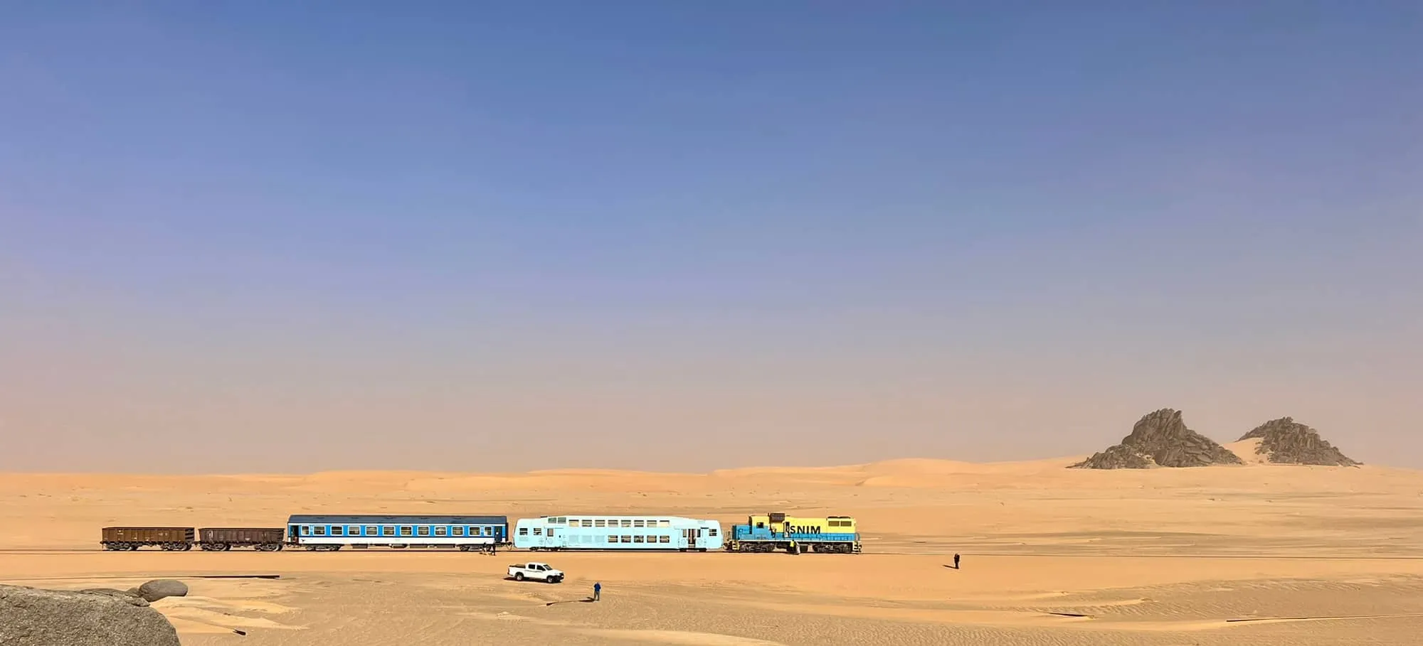 Der Train du Désert in der mauretanischen Sahara, dahinter Felsformationen